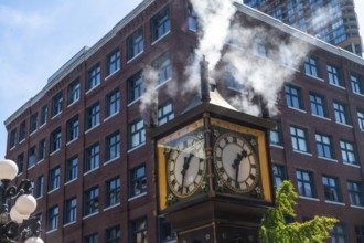 Steam clock releasing vapor against a backdrop of a red brick building and a bright blue sky,