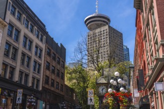 Gastown steam clock with flower decorations rising towards harbour centre, a skyscraper located in