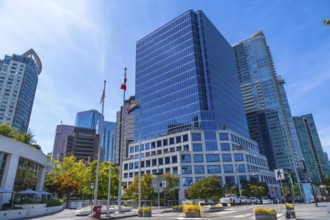 Modern skyscrapers rising against a blue sky, with canadian and pride flags waving in the
