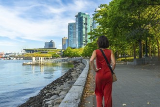 Tourist walking through a park along the waterfront in vancouver, british columbia, soaking in the