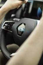 Close-up of a steering wheel with clearly visible logo and hands, Deer E-Carsharing, Renault