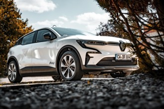 White electric car on a stone path, surrounded by trees, in sunshine, Deer e-Carsharing, Renault