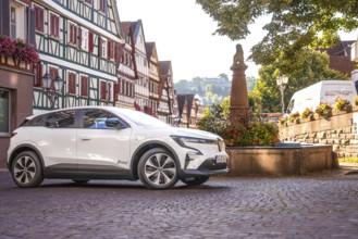 White Renault parks at a fountain in a picturesque old town, Deer e-Carsharing, Renault Megane,