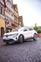 Renault Auto drives down the paved street of a historic town, Deer e-Carsharing, Renault Megane,