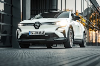 White Renault car in front of a modern glass building at sunset, Deer e-car sharing, Renault