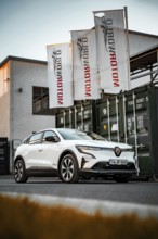 White electric car parked in front of a Motorworld container, urban environment, Deer e-car