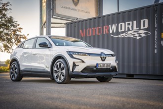 A white electric car stands in front of a Motorworld container with good lighting, Deer