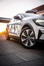 White car at sunset with reflective surfaces in front of urban architecture, Deer e-car sharing,