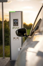 A vehicle is parked at a charging station in a rural area at sunset, Deer E-Carsharing, Renault