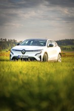 White car in a green natural setting under cloudy sky, Deer E-Carsharing, Renault Megane, Calw,