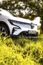 White car parked on a green field in sunlight next to trees, Deer E-Carsharing, Renault Megane,