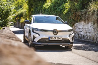 White car on a country road next to a stone wall in the sun, Deer e-car sharing, Renault Megane,