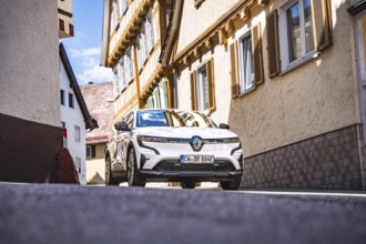 Renault on a sunny road between buildings with traditional architecture, Deer e- car sharing,