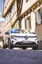 White car in front of a half-timbered house on a sunny city street, Deer E-Carsharing, Renault