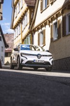 A car drives through a sunlit street in a charming residential area, Deer E-Carsharing, Renault