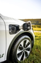 A white electric car is being charged on a green field, Deer e-Carsharing, Renault Megane, Calw,