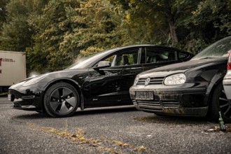 Two black cars side by side in a tree-lined parking lot, Deer e-car sharing, Tesla Model 3, Calw,