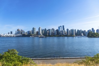 Panoramic view of vancouver's modern skyline rising above the calm pacific ocean on a sunny day,