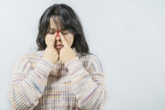 Asian woman with rhinitis touching nose. Close up of young woman with sinus pain touching nose