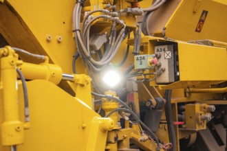 Close-up of yellow machine parts with cables and technical details, tamping machine on Hermann,