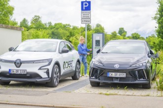 Two electric cars are parked at a charging station in a parking lot in natural surroundings, Deer