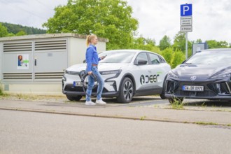 A woman prepares the charger for electric cars in a parking lot, Deer E-Carsharing, Calw, Germany