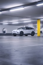 White car in empty underground garage with yellow pillar and neon light atmosphere, deer e-car
