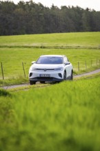 SUV on a path between vast green fields, deer e-car sharing, VW ID4, Calw, Germany