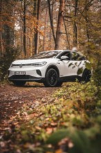White car in autumn forest on a dirt road, Deer E-Carsharing, VW ID4, Calw, Germany