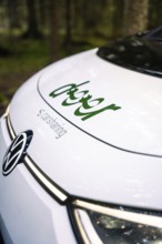Close-up view of the hood of a car with car sharing logo in the forest, Deer E- Carsharing, VW ID3,