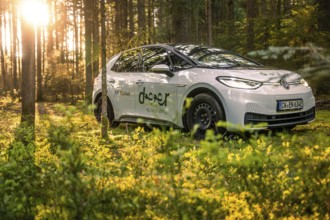 A car drives through a sun-drenched forest in soft evening light, Deer E-Carsharing, VW ID3, Calw,