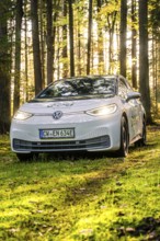A car on a forest path, illuminated by sunlight, license plate CW EN 634E, Deer E-Carsharing, VW
