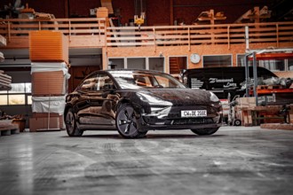 Tesla in a workshop with industrial elements and a building atmosphere, Deer e-Carsharing, Tesla