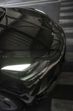 Close-up of a black car with glowing headlights and reflections, Deer E- car sharing, Tesla Model