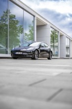 Black Tesla in front of a reflecting glass building on a cloudy day, Deer E-Carsharing, Tesla Model