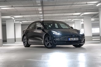 Black Tesla, headlights on, placed centrally in empty parking garage, Deer e-Carsharing, Tesla