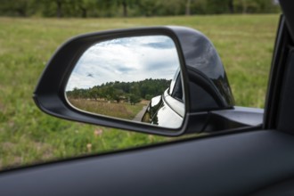 View of a rural road and forest through the car mirror, Deer e-car sharing, Tesla Model 3, Calw,