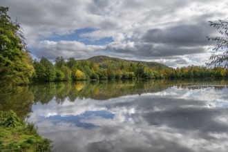 Mixed autumn forest reflected in Happurger Stausee, Happurg, Middle Franconia, Bavaria, Germany