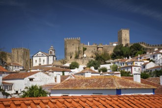 Obidos features a stunning medieval castle rising above white houses and terracotta rooftops,