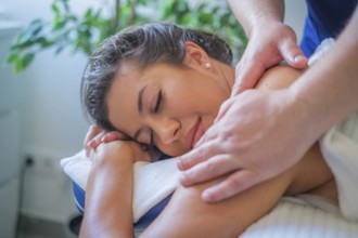 A woman enjoys a soothing back massage by a professional therapist using oil in a serene spa salon