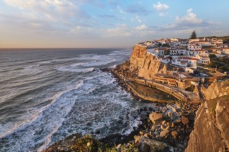 The picturesque village of Azenhas do Mar is illuminated during sunset, resting on cliffs above the