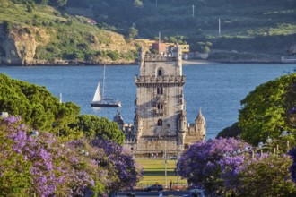 Blooming jacaranda trees line the street as Belem Tower stands majestic over the Tagus River at