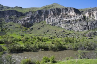 Rocky cliffs and flowing river in a green setting. Picturesque scenery, Kura river, cave monastery,