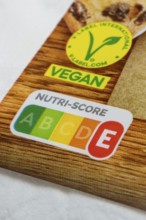 Food label with Nutri-Score E and vegan seal on wooden surface