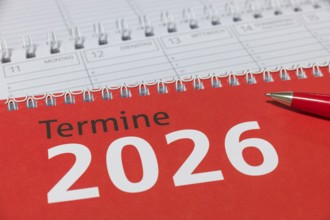 Red 2026 calendar with spiral binding and a red pen, diary