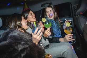 Young happy women friends are enjoying a new year's eve celebration or party inside a car, toasting