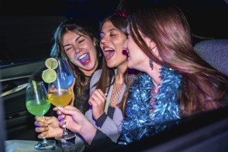 Three young women happily celebrating and laughing together in a car at night, holding colorful