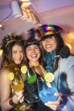 Three happy young women celebrating new year's eve, wearing festive costumes and holding colorful