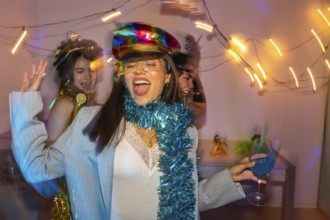 Three cheerful young women dancing and laughing together at a vibrant new year's eve or costume