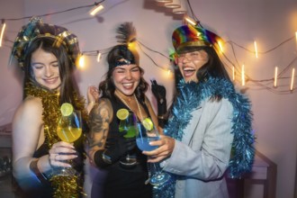 Three young women friends enjoying a fun new year's eve party, celebrating with colorful cocktails,